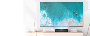  VAVA Chroma Ultra Short Throw Triple Laser Projector on top of a wooden table projecting an ocean scene onto a projector