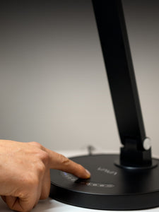 Person touching the digital touch controls on a black VAVA desk lamp