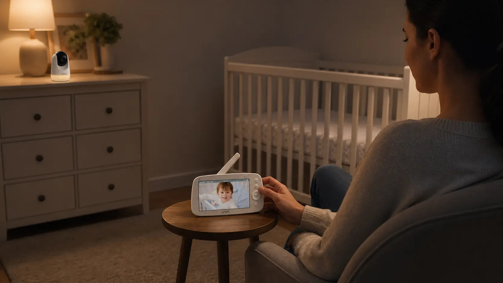 A parent watches a smiling baby on a handheld monitor while a camera monitors the nursery.
