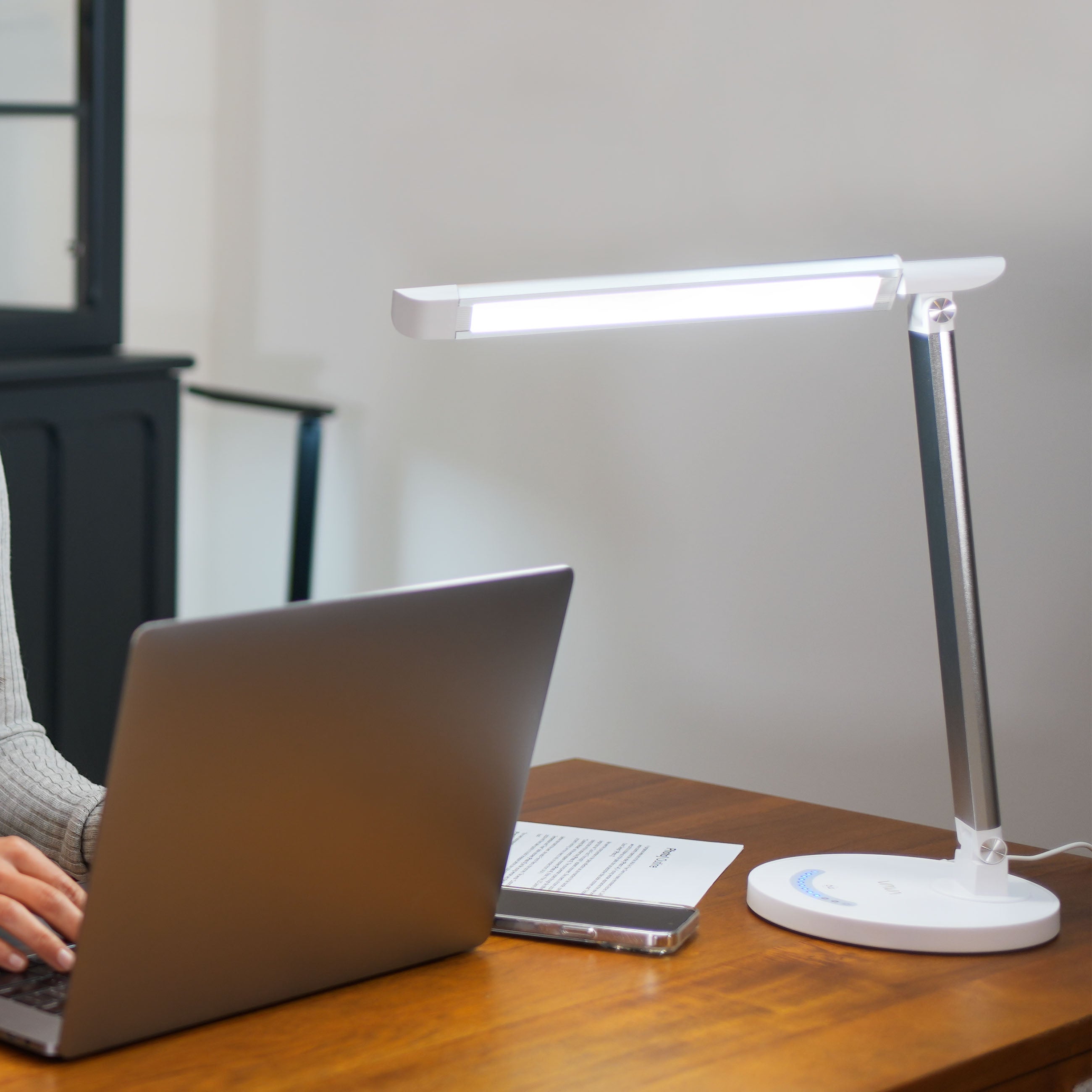 Woman working on her laptop with a white VAVA desk lamp next to her