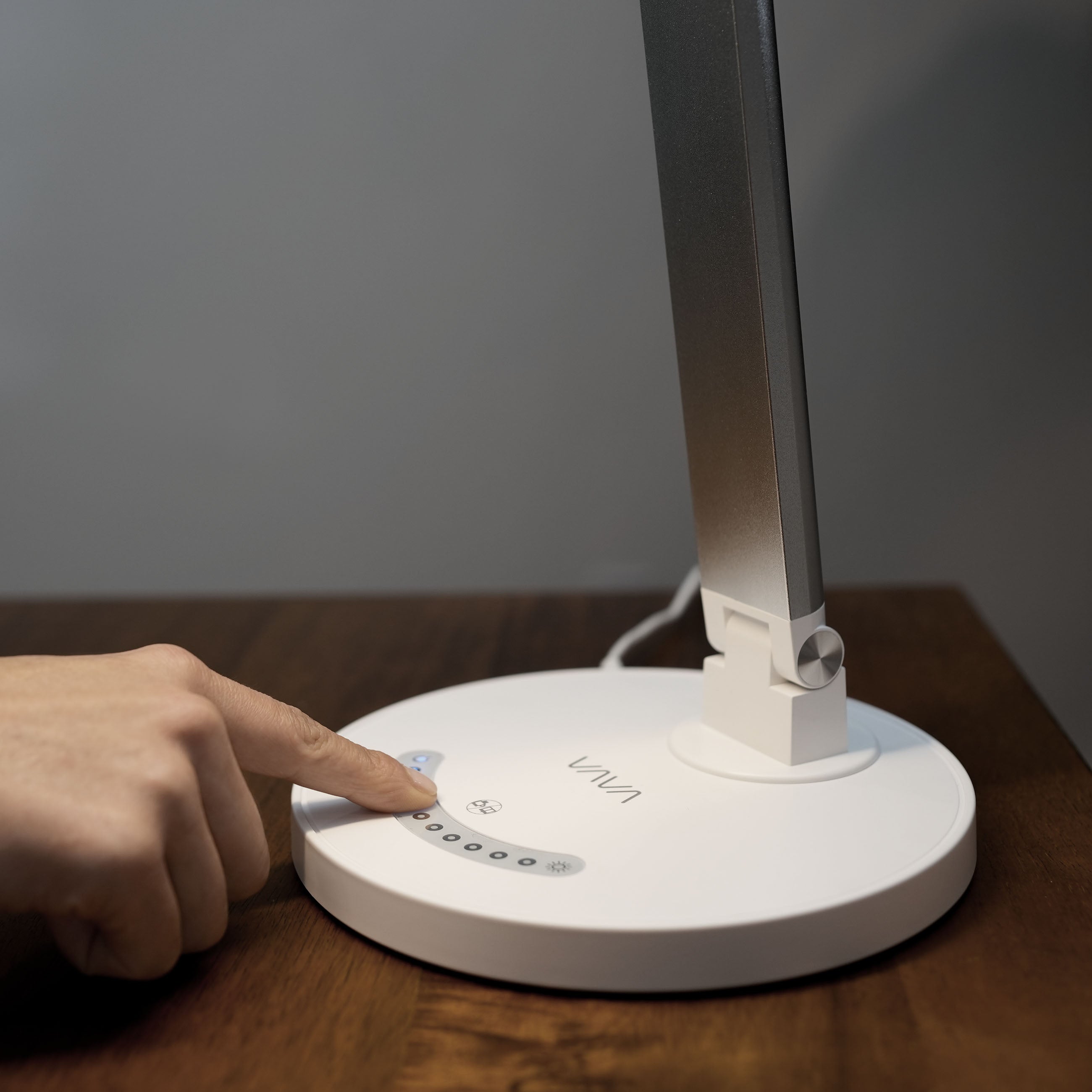  touching the digital touch controls on a White VAVA desk lamp to adjust brightness