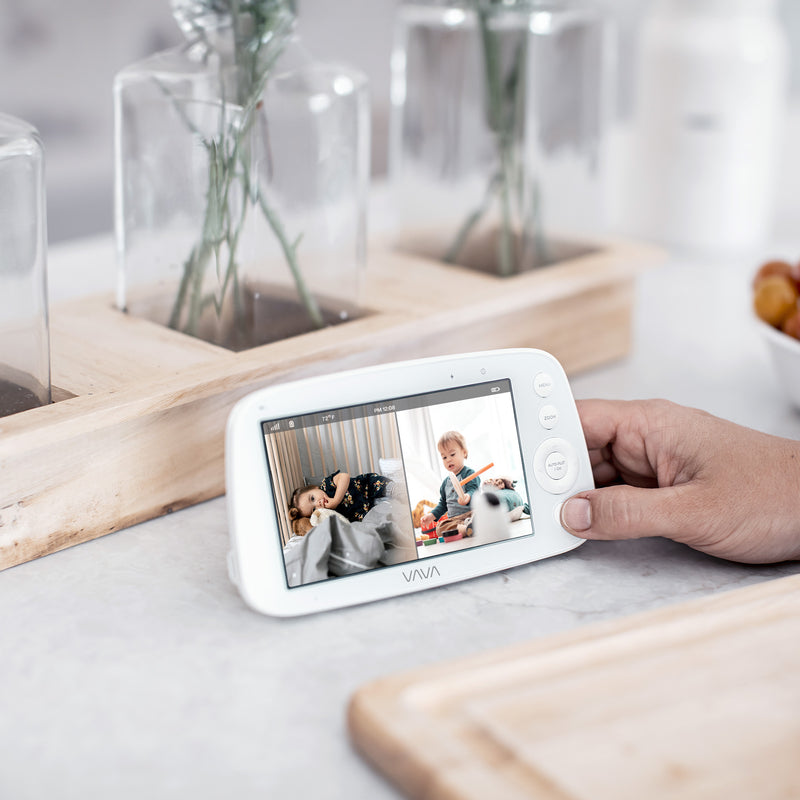 Caregiver holding a VAVA Baby Monitor Parent Unit in split screen mode