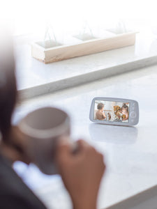 Caregiver holding a cup, VAVA split screen baby monitor on a white counter
