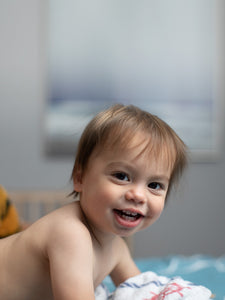 Smiling baby in a diaper with a stuffed tiger in the background