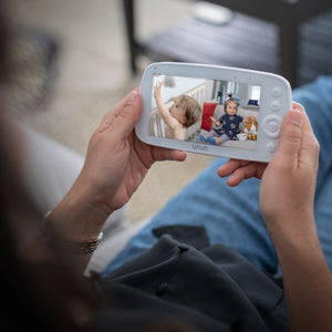 Caregiver holding a VAVA split screen baby monitor