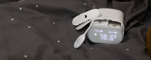 VAVA smart baby thermometer, silicone wand, two adhesive patches on a gray and white polka dot blanket