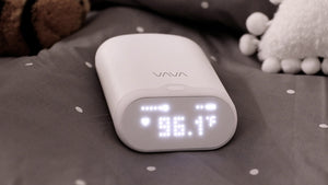 VAVA smart baby thermometer on a gray and white polka dot blanket