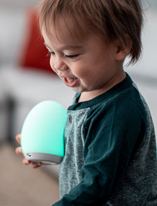 Toddler boy holding a green VAVA baby night light