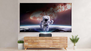 VAVA Chroma on top of a wooden table projecting a space scene onto a screen