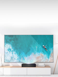  VAVA Chroma Ultra Short Throw Triple Laser Projector on top of a wooden table projecting an ocean scene onto a projector