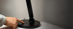 Person touching the digital touch controls on a black VAVA desk lamp