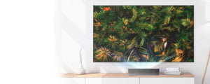 VAVA 4K Laser TV projector on a white and wood table projecting a nature scene onto an ALR screen pro