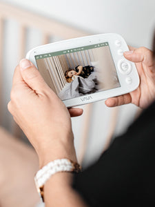 Caregiver holding a VAVA baby monitor with a baby on the screen