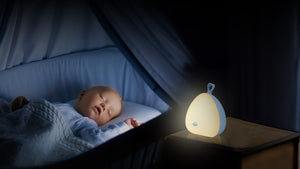 The VAVA Peep-a-Light on a nightstand with a sleeping baby in the background