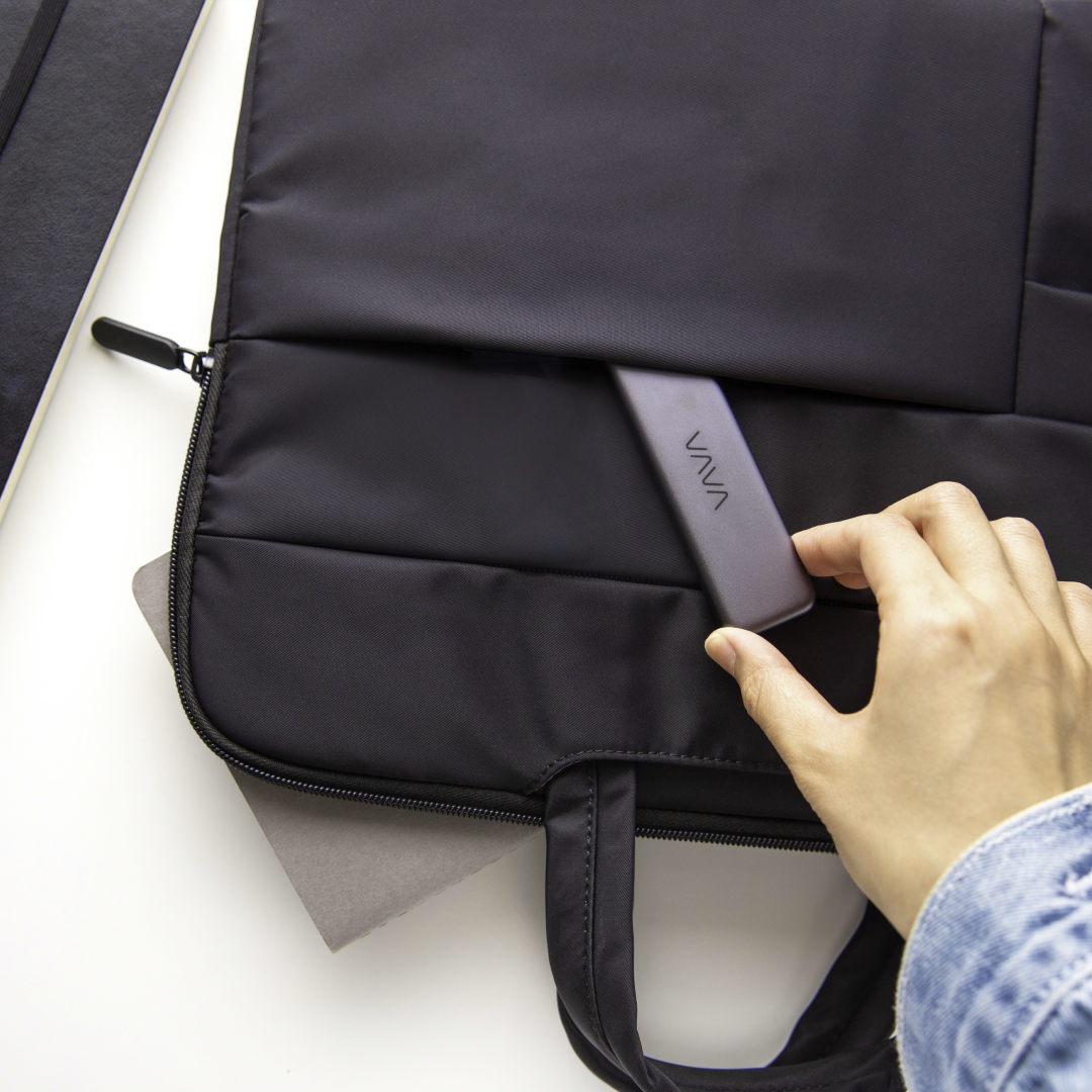 Hand tucking a VAVA portable SSD into a black bag