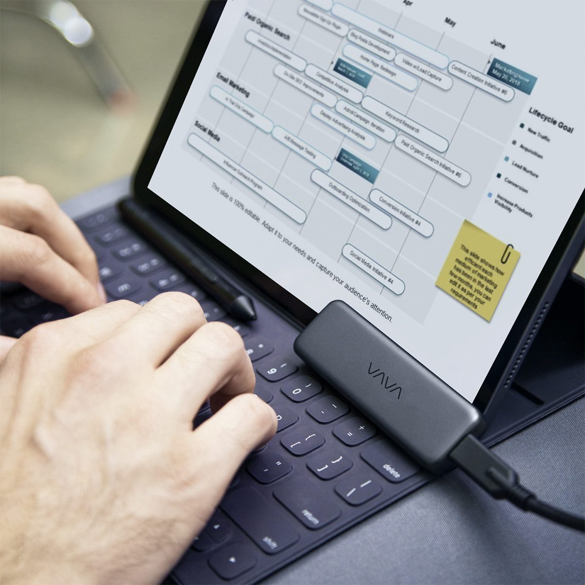 Hands typing on a laptop hooked up to a VAVA portable SSD