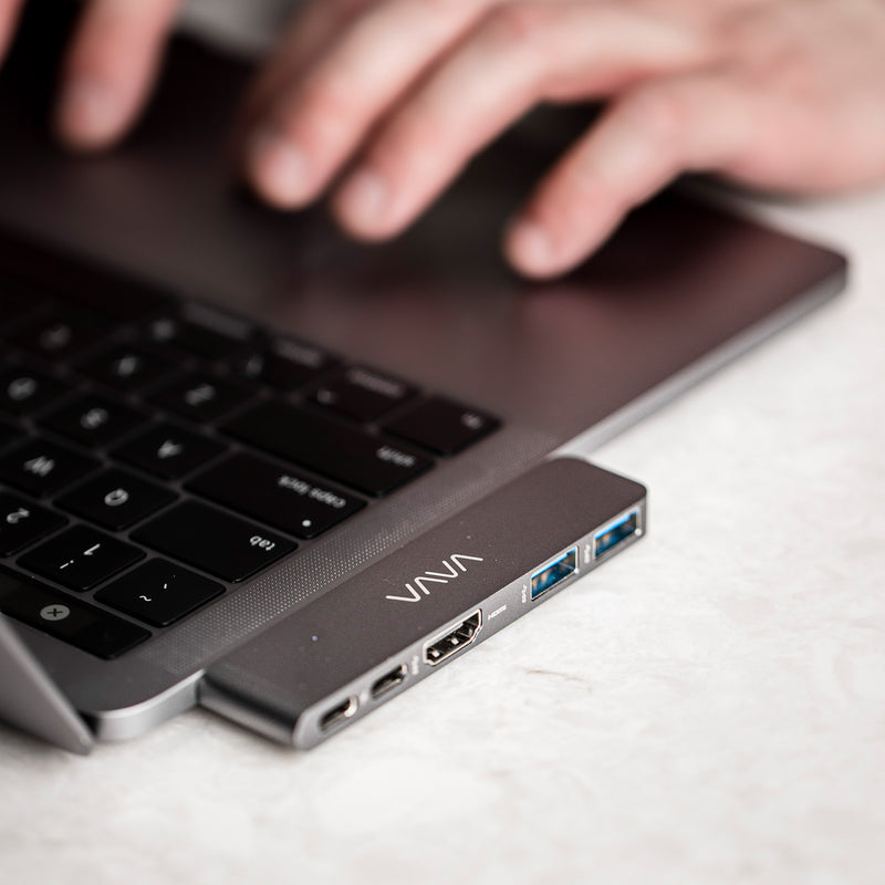 Hands typing on a laptop keyboard connected to a VAVA 5-in-2 USB-C Hub