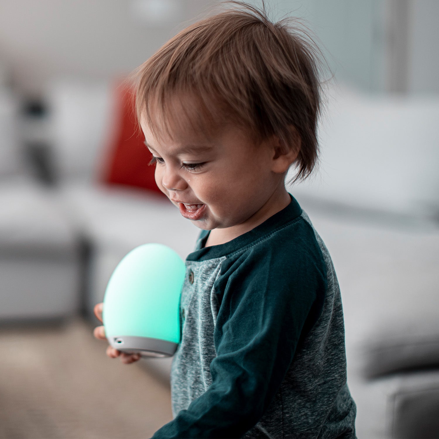 Toddler boy smiling and holding a green VAVA baby night light